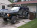 1988 Ford Bronco - This modified Jeep Cherokee XJ is parked in a driveway next to a house and trash cans.
