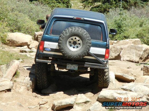 1996 Ford Bronco rear view, dark blue and silver, on rocky terrain