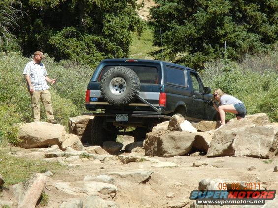 1996 Ford Bronco navigating rocky terrain with two people nearby