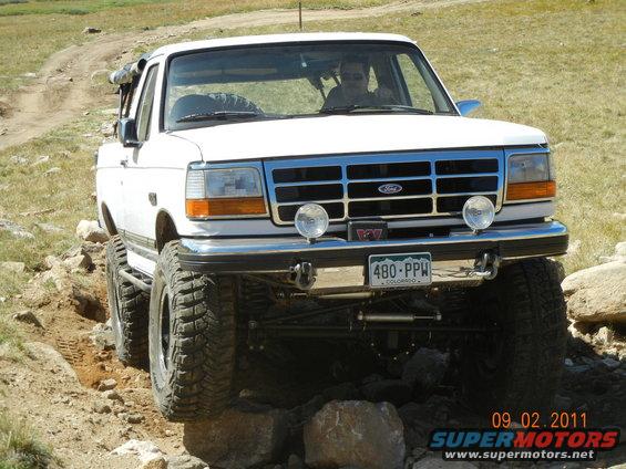 White Ford F-Series truck on rocky trail. Has a spare tire on roof rack