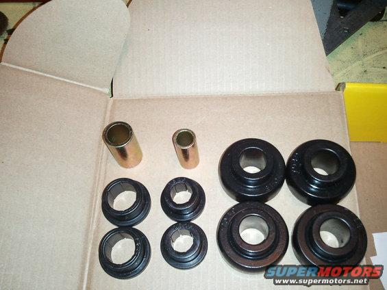 Set of black suspension bushings and gold metal sleeves laid out in a cardboard box