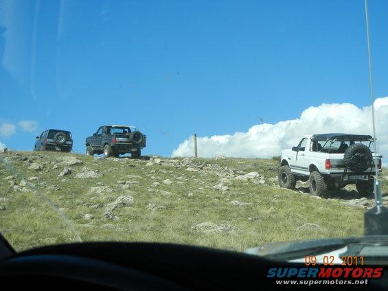 White 1996 Ford Bronco on a grassy hill with two other SUVs