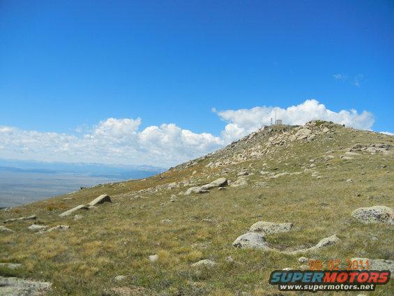 Mountain landscape with radio tower on summit under blue sky with clouds. Date stamp reads 08-02-2011