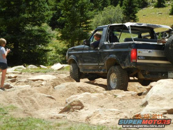 Black 1996 Ford Bronco convertible off-roading on a rocky trail