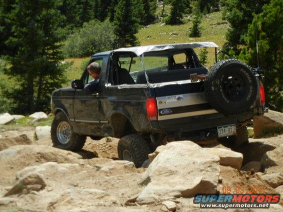 Black 1996 Ford Bronco driving over rocks on a trail