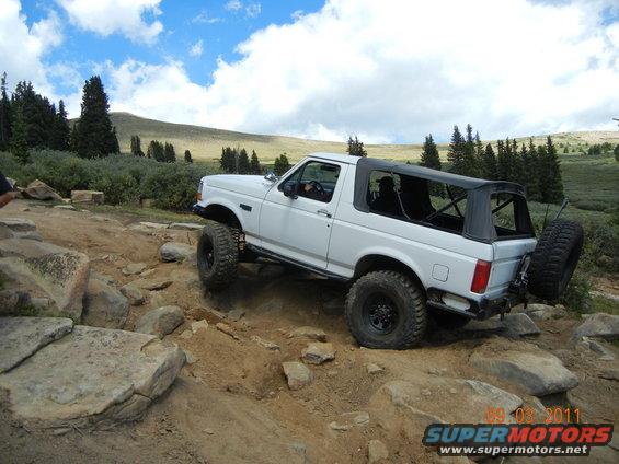 White 1996 Ford Bronco convertible off-roading on a rocky mountain trail
