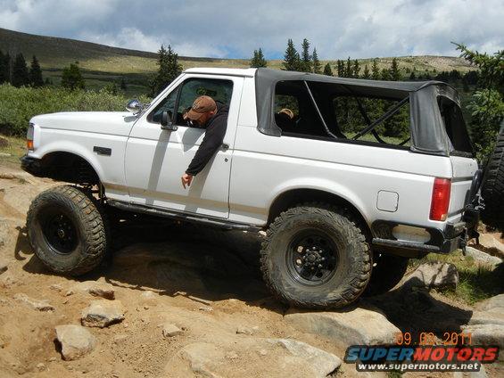 White 1996 Ford Bronco with soft top navigating rocky terrain