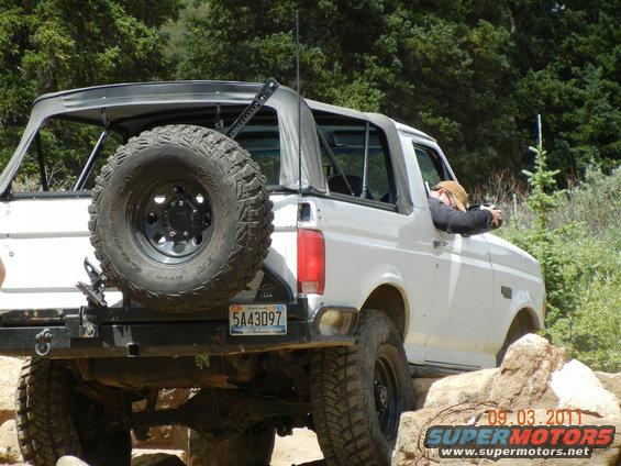 White Ford Bronco on rocky trail, driver leaning out window