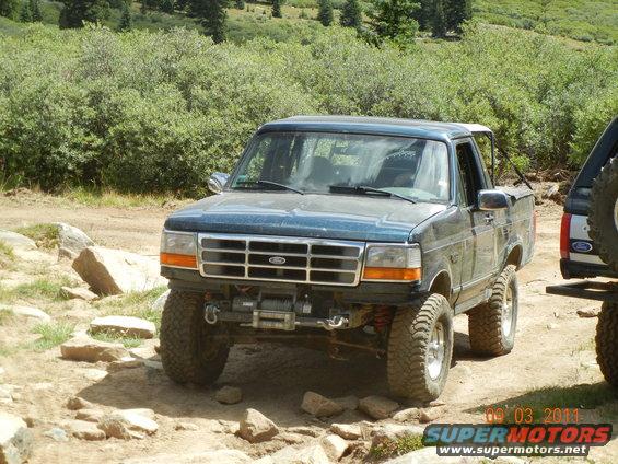 Dark blue 1995 Ford Bronco with winch and off-road tires on a rocky trail