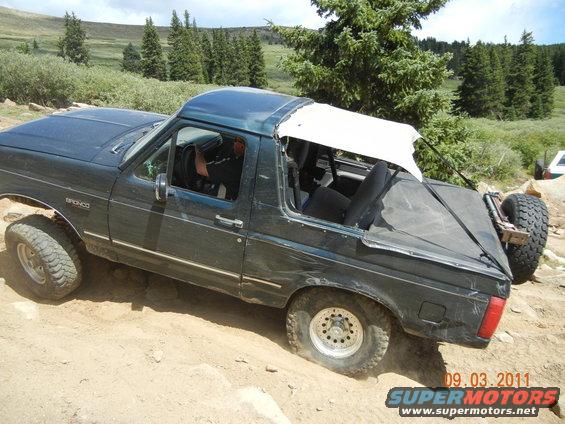 Dark green 1996 Ford Bronco with removable top on rocky terrain