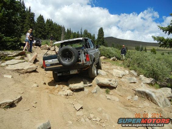 Gray Ford Bronco with spare tire on rear, navigating rocky terrain
