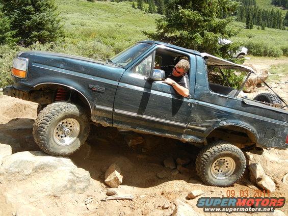 1996 Ford Bronco navigating a steep, rocky off-road trail with a driver inside