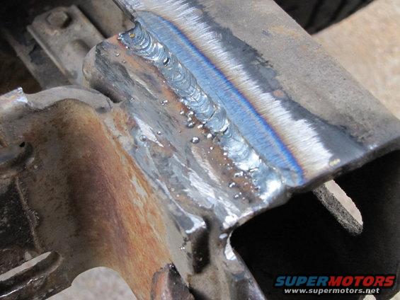 Close-up of freshly welded metal frame section with visible weld beads and heat discoloration