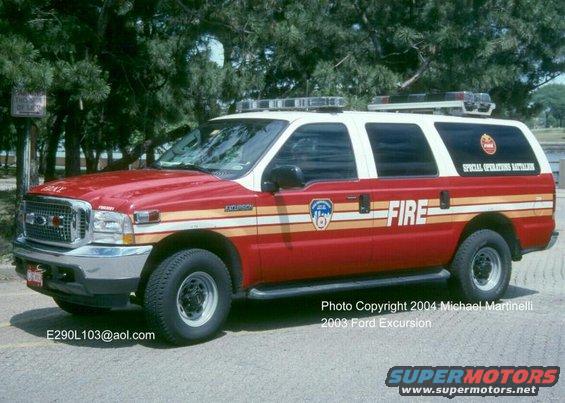 Red and white Ford Excursion fire vehicle, side view