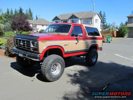 1984 Ford Bronco lifted with large tires, red and tan two-tone paint