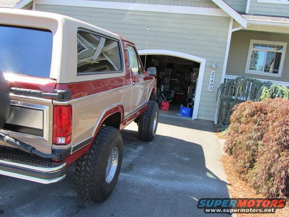 Two-tone red and tan Ford Bronco parked in driveway, rear view