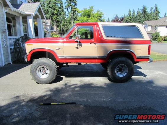 Side view of red and tan Ford Bronco with lifted suspension and large tires