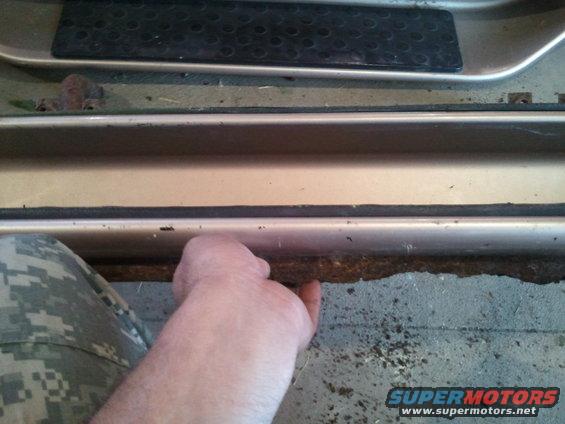 Close-up of the driver's side door sill and floor area of a 1996 Ford Bronco, showing some wear and tear
