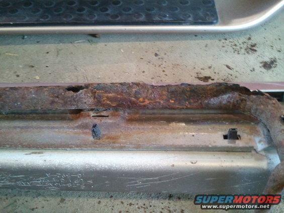 rusted out rocker panel on a vehicle, showing significant corrosion and damage