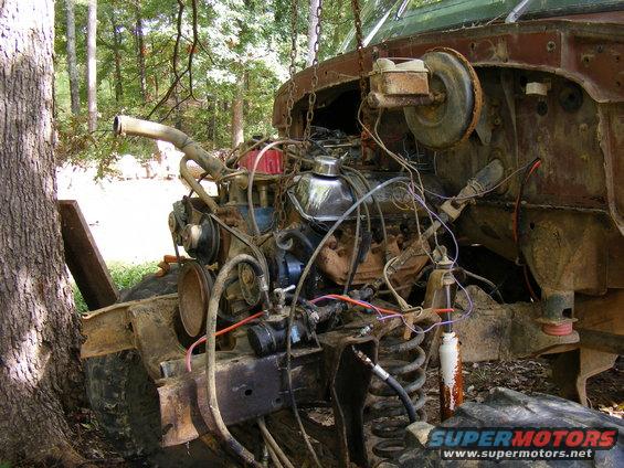 Rusty engine and suspension components of a disassembled vehicle, suspended by chains