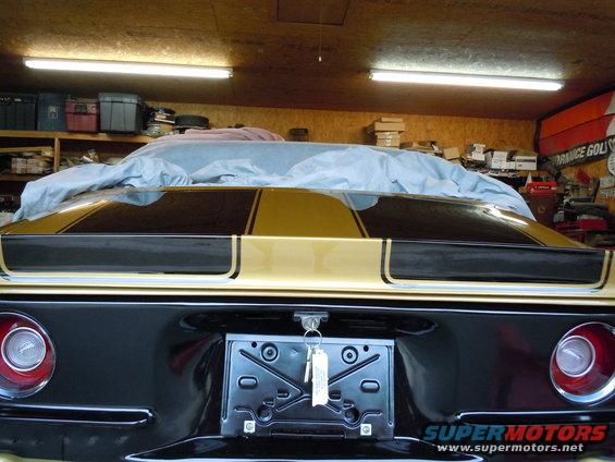 1970 Chevrolet Camaro rear with gold and black stripes, covered partially with a car cover