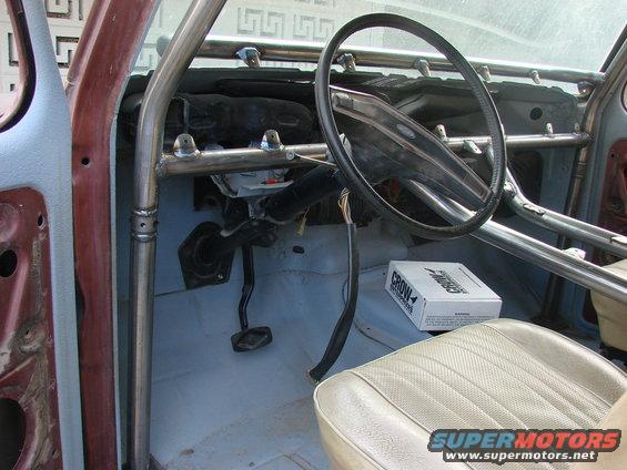 Interior view of a vehicle with a prominent roll cage, beige seat, and a box labeled CROW