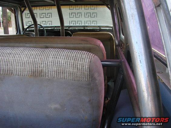 Interior view of a vehicle with patterned fabric seats, a roll cage, and a steering wheel visible