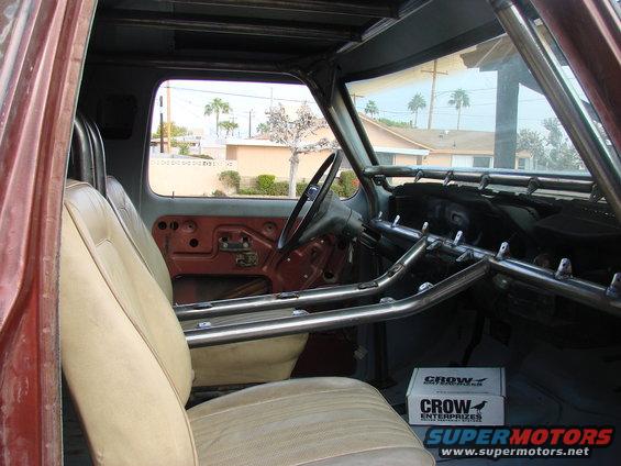 Interior view of a vehicle with a prominent roll cage and tan seats. Box with 'CROW ENTERPRISES' visible