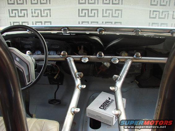Interior of a vehicle with a roll cage, showing steering wheel, dashboard, and a box labeled 'Crow Enterprises'