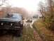 1986 Ford Bronco - A group of SUVs and off-road vehicles are stuck in a muddy trail during autumn, with trees and fog surrounding them.