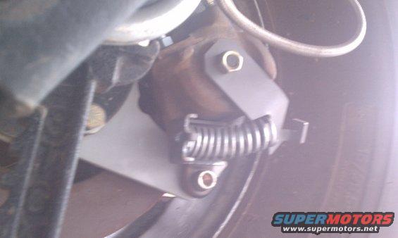 Close-up of a vehicle's parking brake mechanism with a spring and bracket