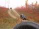 1986 Ford Bronco - Two off-road vehicles navigate a muddy track through autumn foliage.