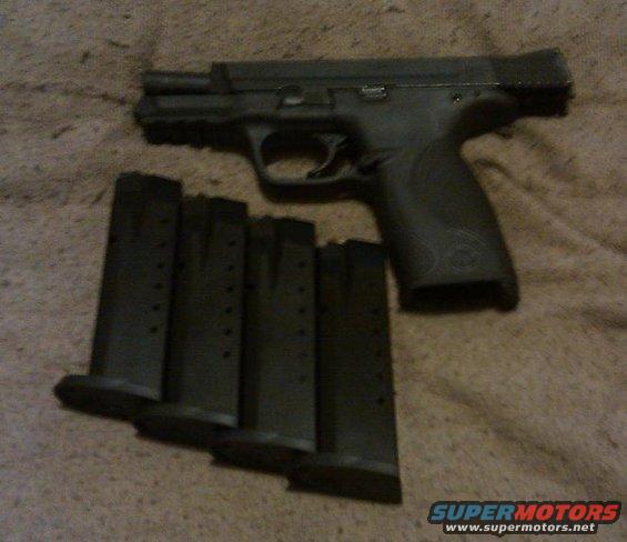 Black pistol with four magazines on a textured surface