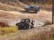 1986 Ford Bronco - Two off-road vehicles, a 1986 Ford Bronco and a Suzuki Samurai, navigate a muddy track.