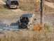 1986 Ford Bronco - Off-road vehicles navigate a muddy trail, with one vehicle deeply stuck in the mire.