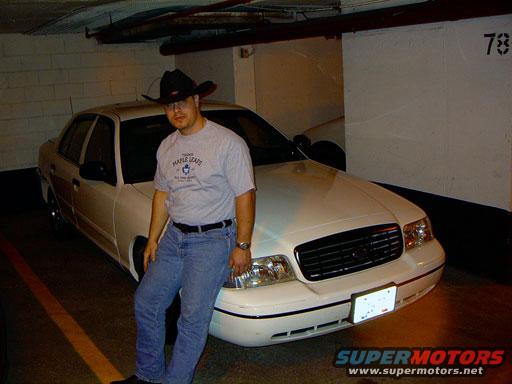 White 1999 Ford Crown Victoria front 3/4 view with a man leaning on it
