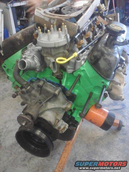 V8 engine on an orange stand, green block, distributor cap, oil filter attached