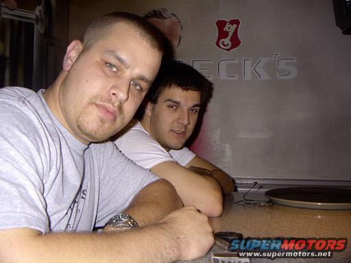 Two guys sitting at a bar with a "Beck's" sign behind them