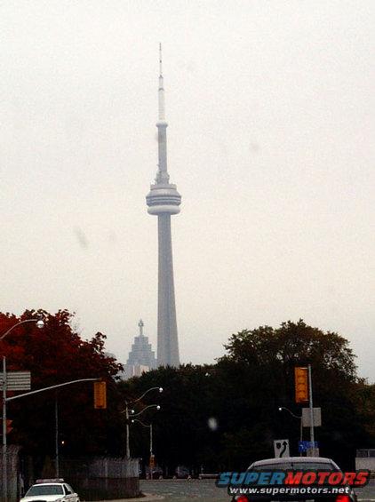 distant view of the CN Tower with trees and traffic lights in the foreground