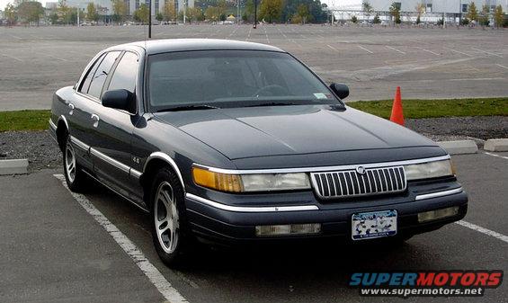 Dark sedan parked in a lot, front quarter view. It has a chrome grille and chrome trim