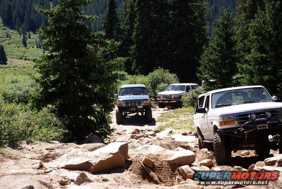 Three Ford Broncos on a rocky mountain trail, one in the foreground