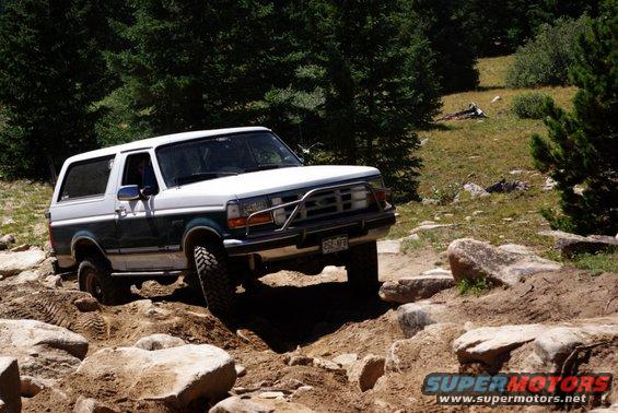 White and green Ford Bronco navigating a rocky trail