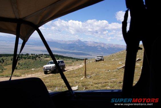 two SUVs driving on a dirt road in the mountains