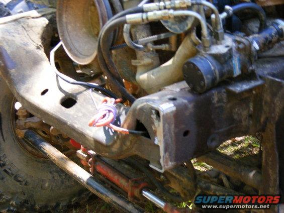Close-up of vehicle frame with engine parts and hydraulic lines visible