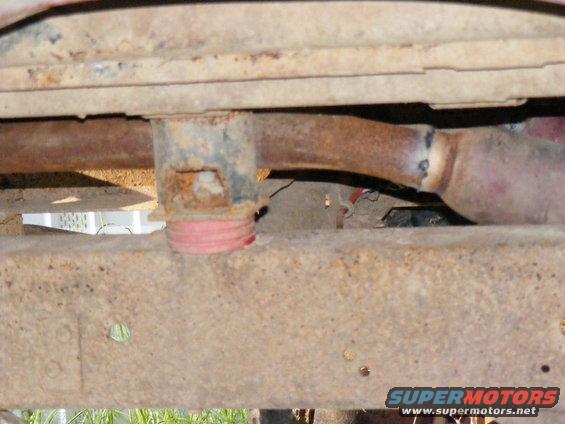 Undercarriage view of rusty frame and exhaust pipe with red bumper stop