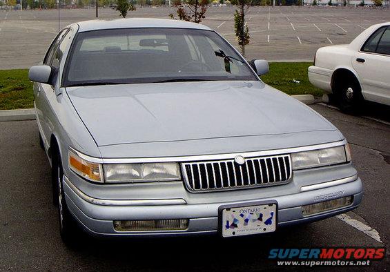 Silver Mercury Grand Marquis parked in a lot, with a white police car in the background. Ontario license plate visible