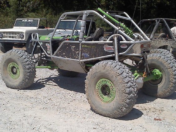 Custom green and silver off-road buggy parked next to a white 1969 Ford Bronco