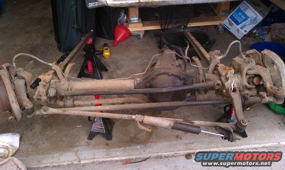 Front axle assembly with steering components and shock absorber, resting on jack stands