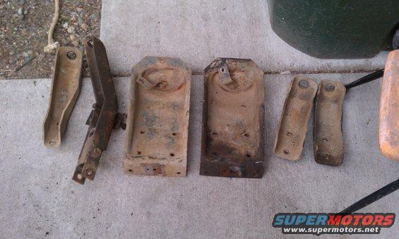 Several rusty metal vehicle suspension parts laid out on concrete
