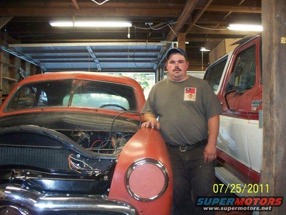 Man with vintage car, hood open, next to red and white truck